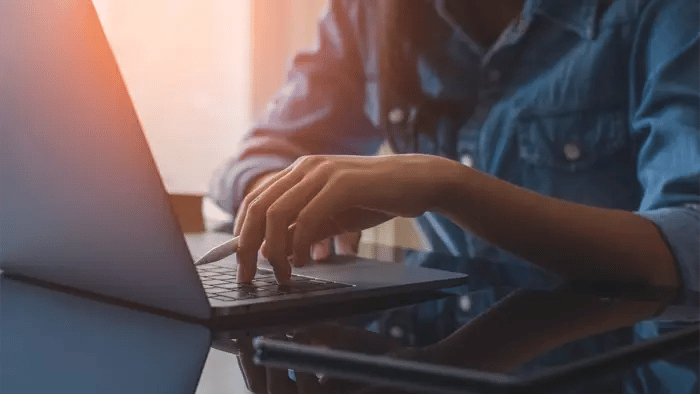 person typing on laptop in blue shirt