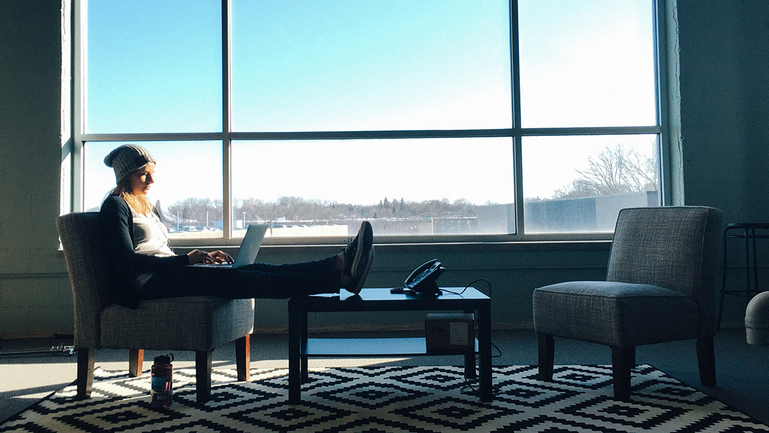 someone sitting in a window working on a laptop